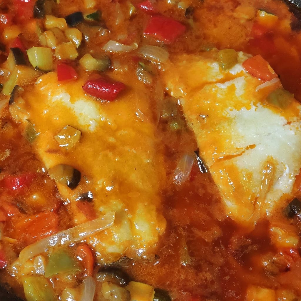 dos porciones de bacalao en sanfaina con tomate, pimientos, cebolla, calabacín y berenjena