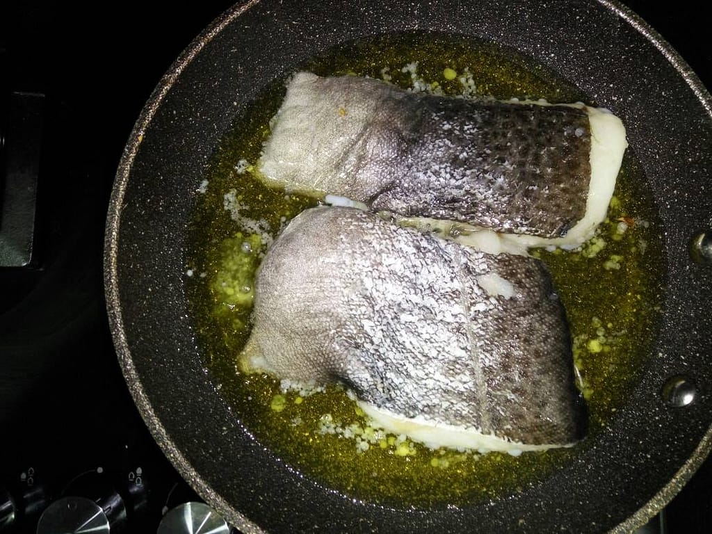 in a frying pan two cod fillets confit in oil