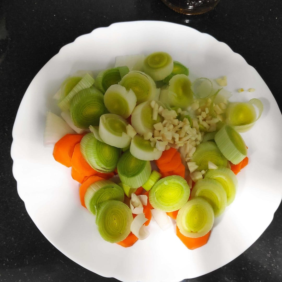 en un plato blanco cortado zanahoria a rodajas, puerro ,cebolla y ajos