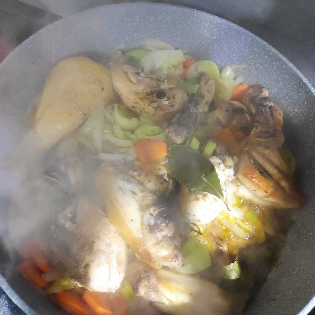 La cazuela con pollo, zanagoria, puerro y ajo cocinándose