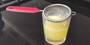 un colador sobre un vaso para colar el zumo de limón