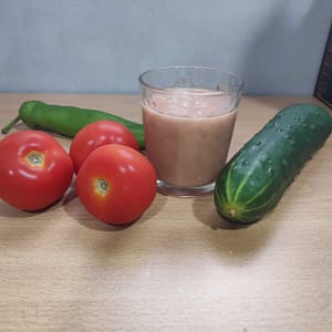 vaso de gazpacho y verduras al lado