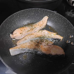 dos escalopines de salmón cocinándose a la plancha