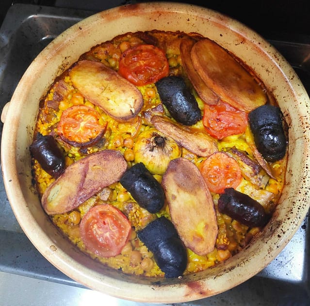 en una cazuela de barro arroz al horno valenciano, con patatas, chorizo , morcilla, bacon, costilla de cerdo.