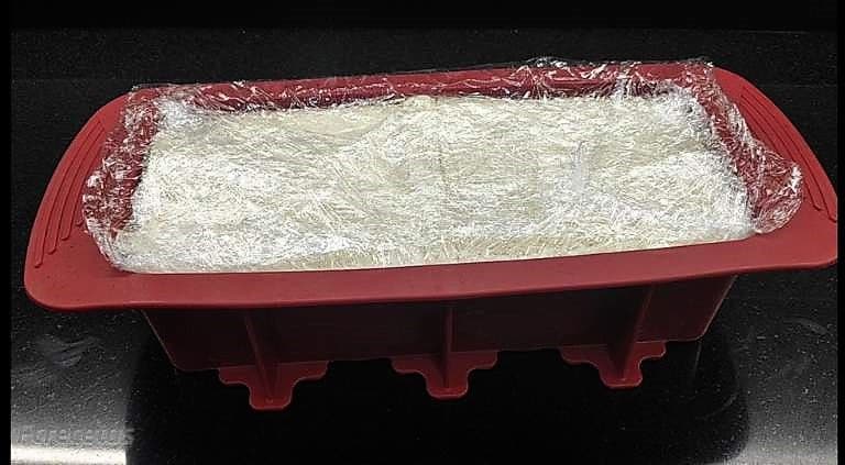 pastel de pan de molde dentro del molde y envuelto con film transparente