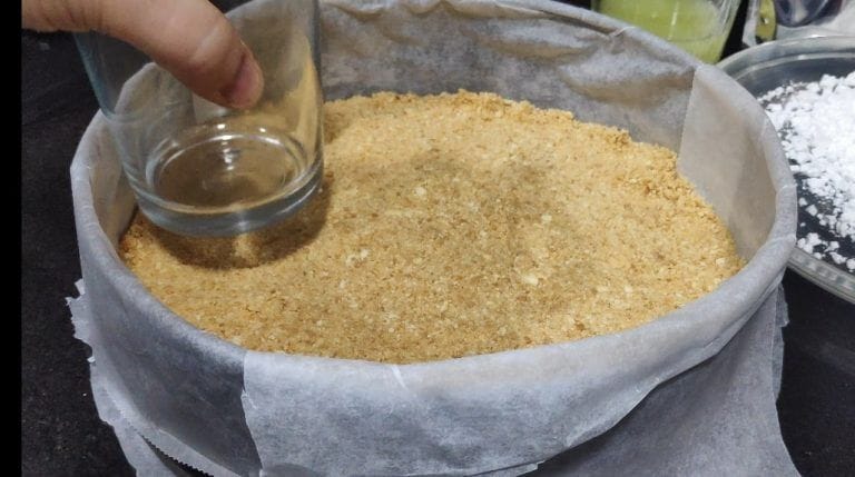 aplanando la base de galleta en el molde con un vaso