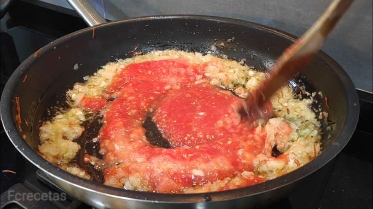 sartén con tomate añadido a la cebolla