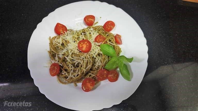 un plato blanco con espaguett al pesto y tomates cherrry