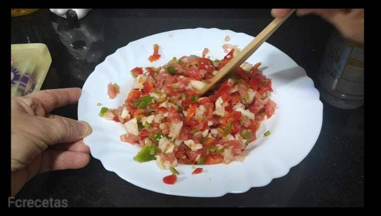 en un plato pipirrana mezclada tomate,cebolla y pimientos a trocitos
