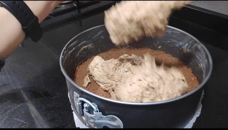 añadiendo el mousse sobre la base de galleta en el molde