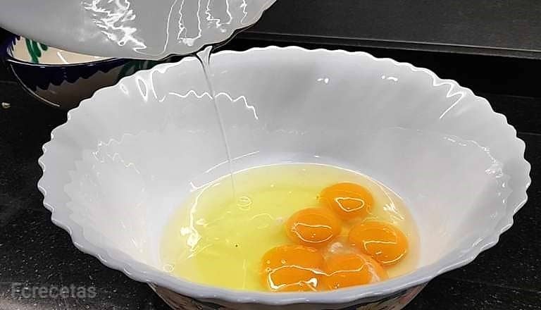 añadiendo azúcar a los huevos en un recipiente blanco