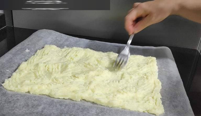 a layer of mashed potatoes on the baking paper