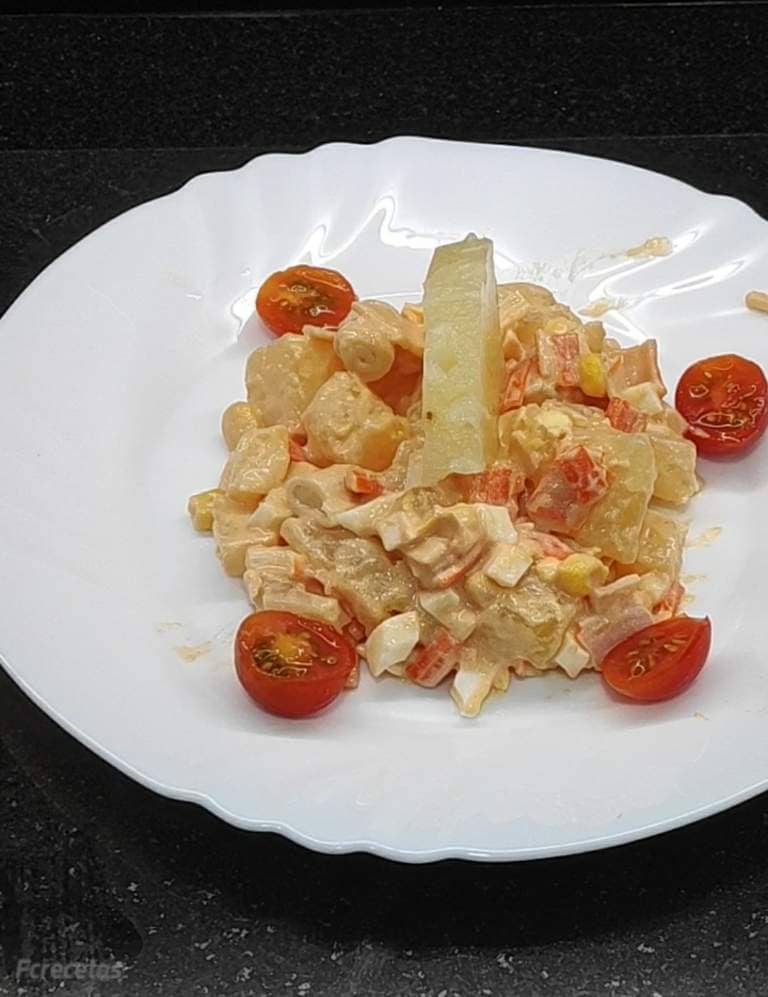 un plato de ensalada de cangrejo decorado con tomates cherry